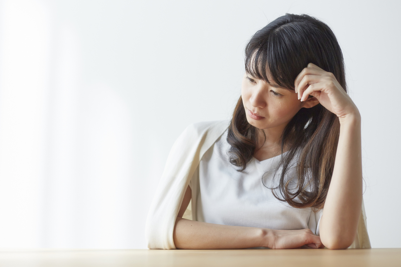 肘をついて悩む女性